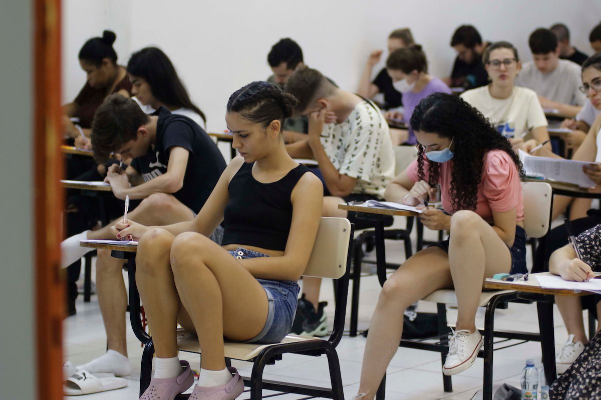 A foto mostra sala de aula com estudantes sentado fazendo prova