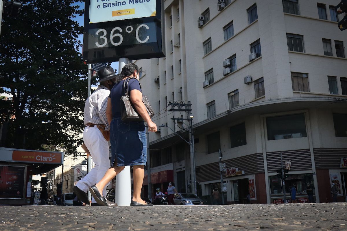 a foto mostra duas pessoas caminhando em uma avenida na área central de Campinas
