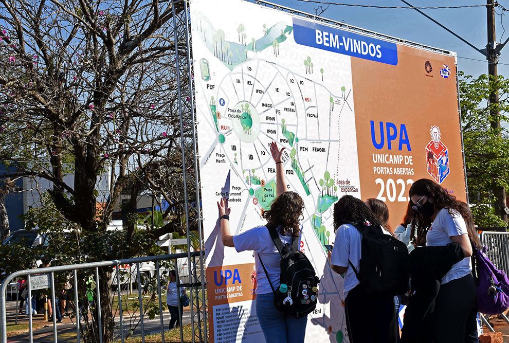 A foto mostra um grupo de estudante olhando um mapa do campus em Campinas