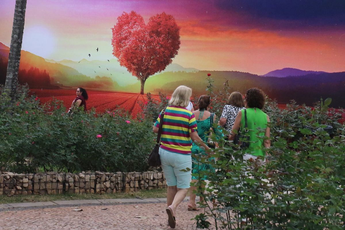 a foto mostra pessoas caminhando pela Expoflora ao fundo é possível ver cenários da festa com um coração de flores
