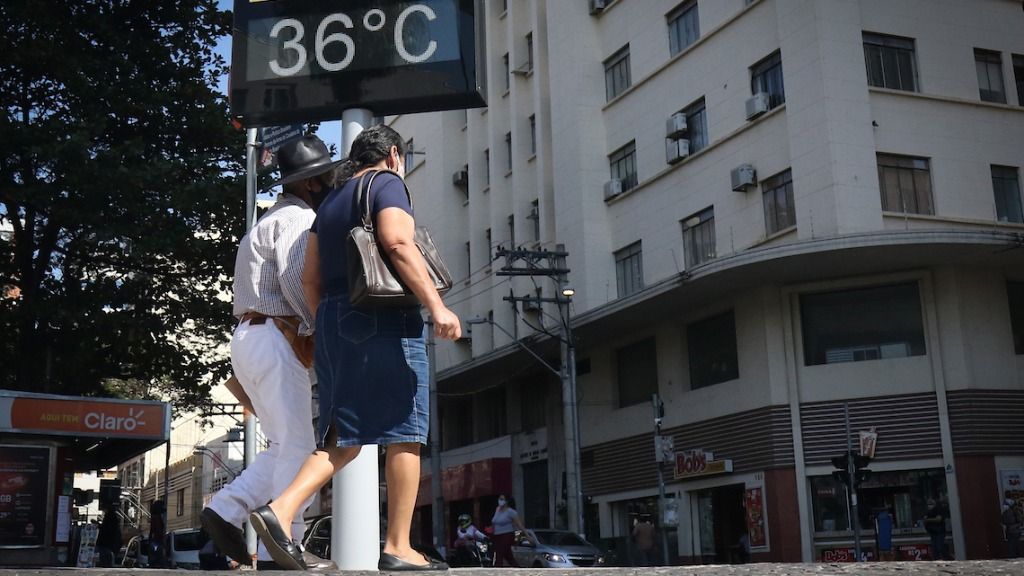 a foto mostra pessoas caminhando no Centro e um termômetro de rua