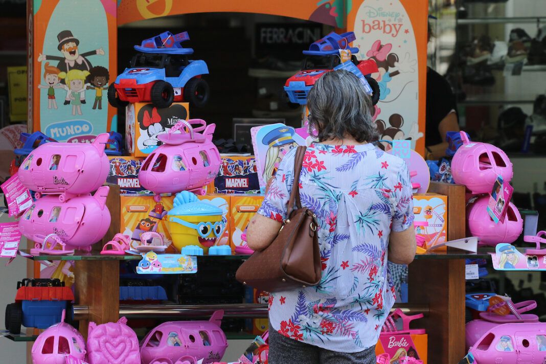 A foto mostra uma mulher olhando uma vitrine de loja no Centro de Campinas repleta de brinquedos