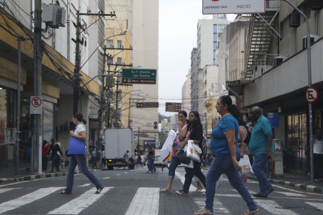 A foto mostra pessoas atravessando rua em Campinas