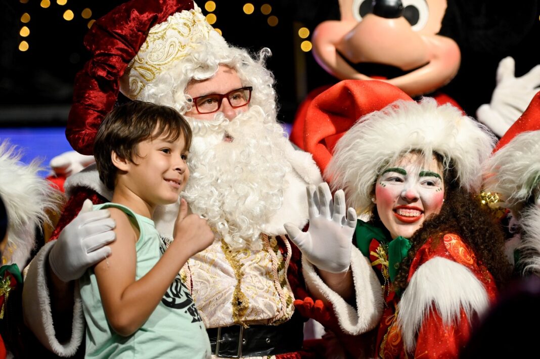 A foto mosrta o Papai-Noel com crianças em sua volta