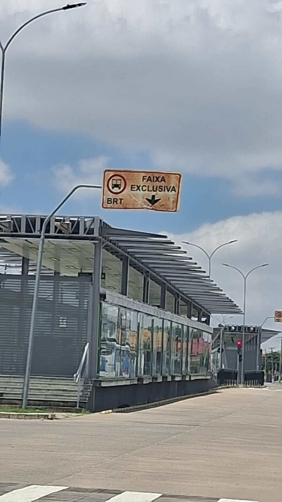 foto mostra placa de sinalização de faixa exclusiva do BRT enferrujada ao lado de um dos pontos do corredor de ônibus