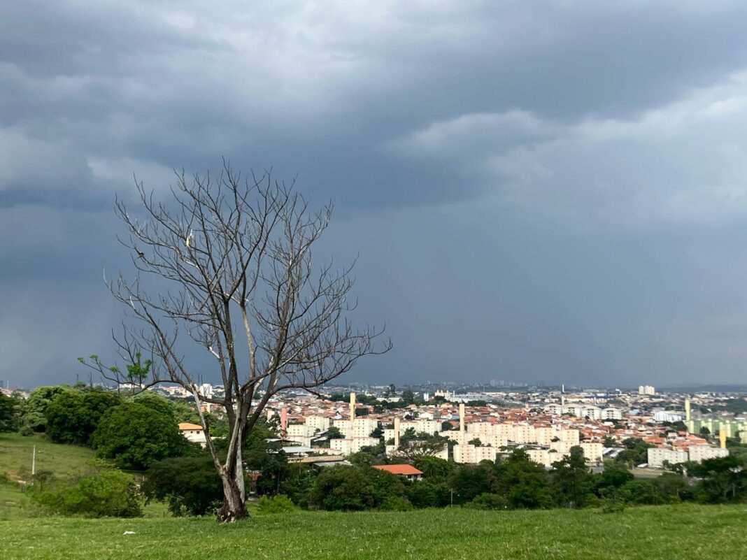 A foto mostra um bairro de Campinas, com casas no horizonte e o céu bastante carregado com nuvens de chuva