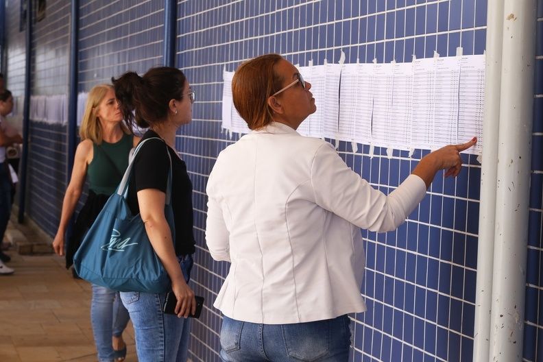 a foto mostra três mulheres vendo as lista de aprovados colados em uma parede