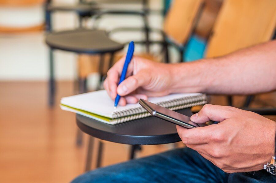 a foto mostra uma pessoa fazendo anotações em um caderno