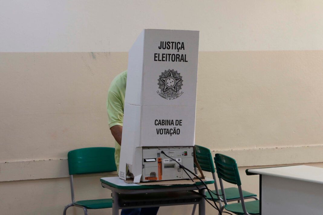A foto mostra eleitor atrás de uma cabine de votação
