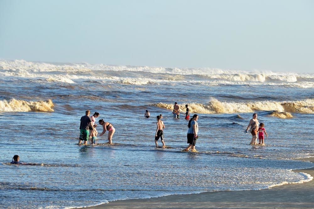 a foto mostra diversos banhistas no mar de uma praia
