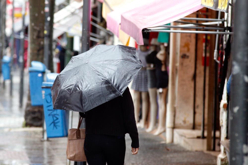 a foto mostra uma pessoa andando na chuva com um guarda-chuva aberto