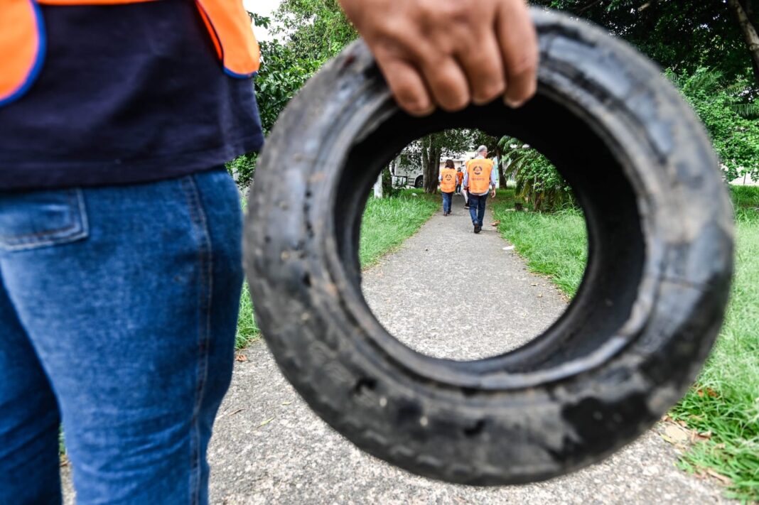 a foto mostra uma pessoa segurando um pneu e no meio dele dá pra ver agentes caminhando