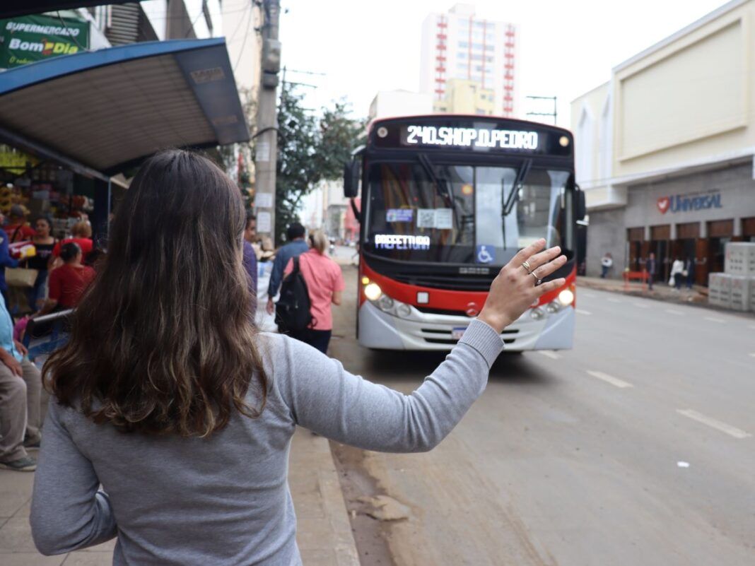 a foto mostra uma mulher sinalizando parada para um ônibus em um ponto da Campos Sales
