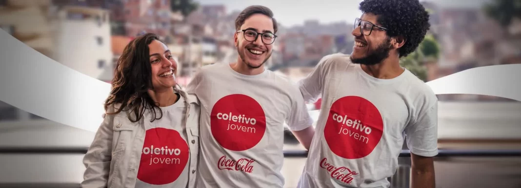 A foto mostra jovens com camisetas do Instituto Coca-Cola abraçados e sorrindo