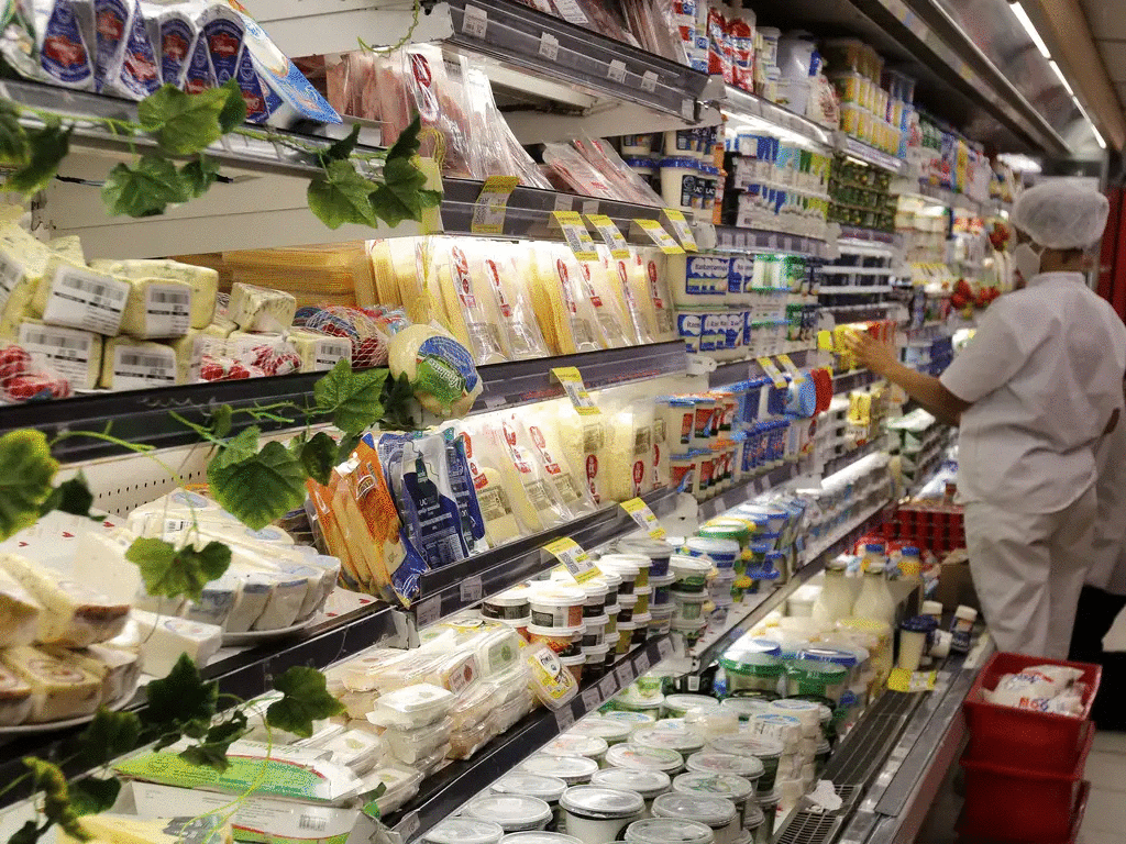 a foto mostra o corredor de um supermercado com alimentos em refrigeradores