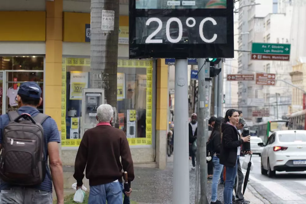 a foto mostra pessoas andando no centro de Campinas com roupas de frio; há um termômetro na calçada marcando 20°C