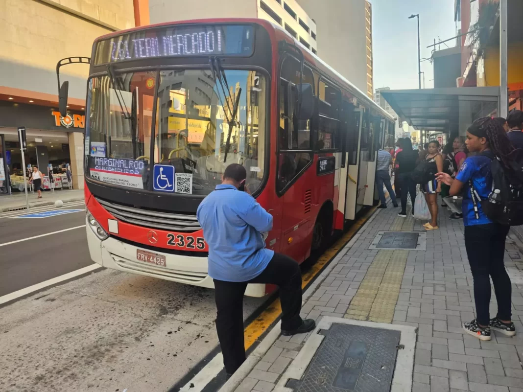 a foto mostra o ônibus parado e pessoas em seu entorno