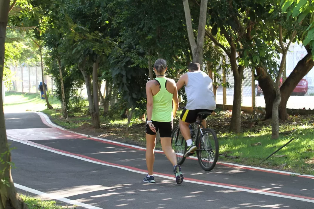 a foto mostra um casal fazendo exercícios em um parque da cidade