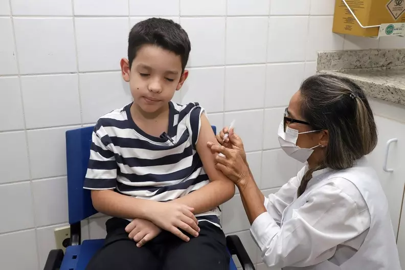 a foto mostra um menino sendo vacinado em um centro de saúde
