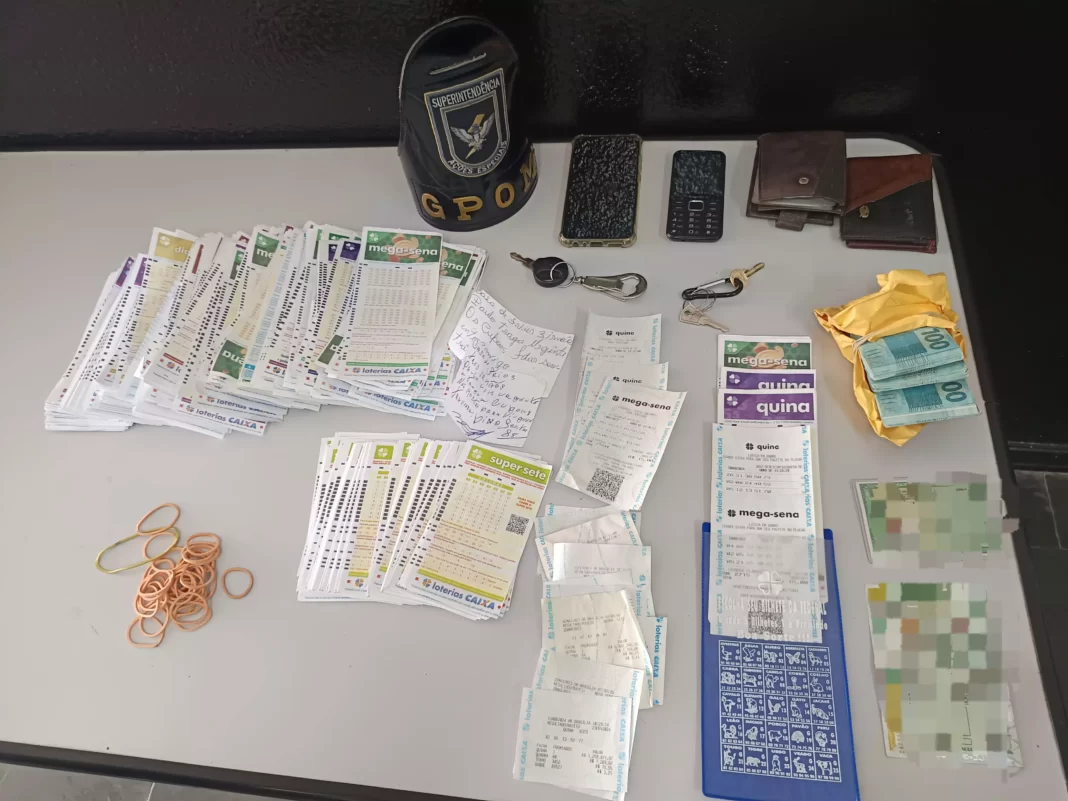 a foto mostra objetos apreendidos pela guarda como talões de loteria e dinheiro falso que foram colocados sobre uma mesa