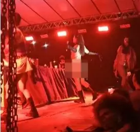 a foto mostra pessoas em cima do palco com uma luz vermelha
