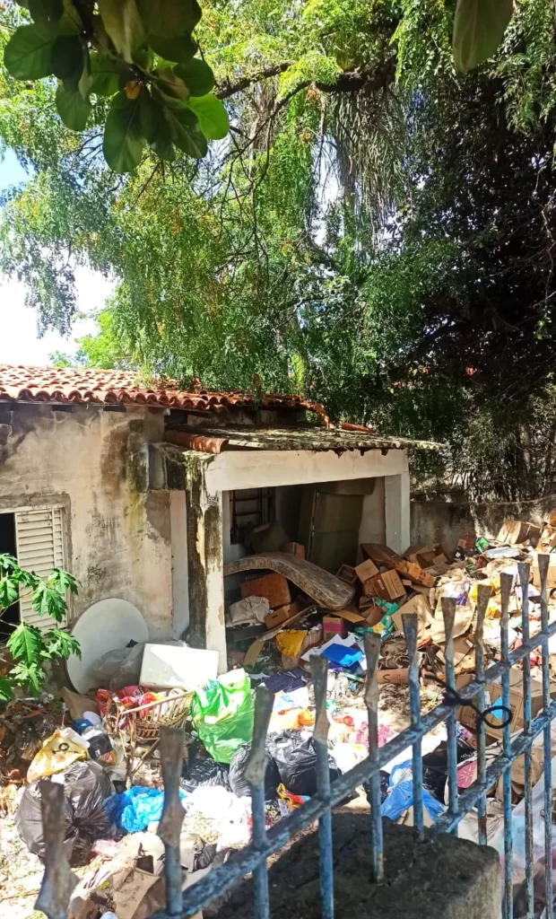 a foto mostra a frente da casa com acúmulo de lixo