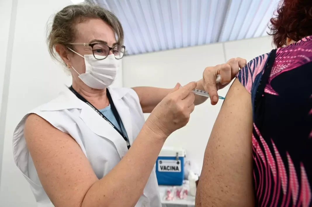 a foto mostra uma profissional da saúde aplicando uma vacina