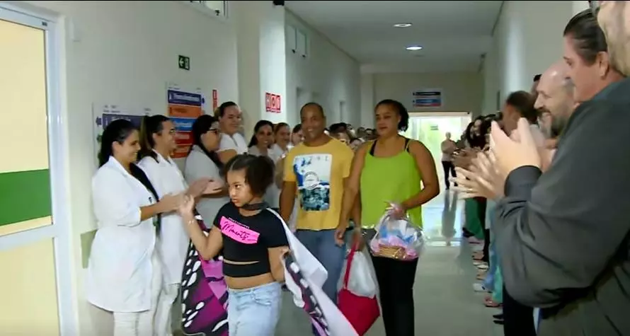 a foto mostra o corredor humano com pessoas aplaudindo a menina
