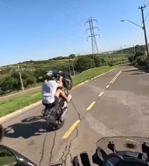 a foto mostra o motoqueiro fazendo manobras perigosas