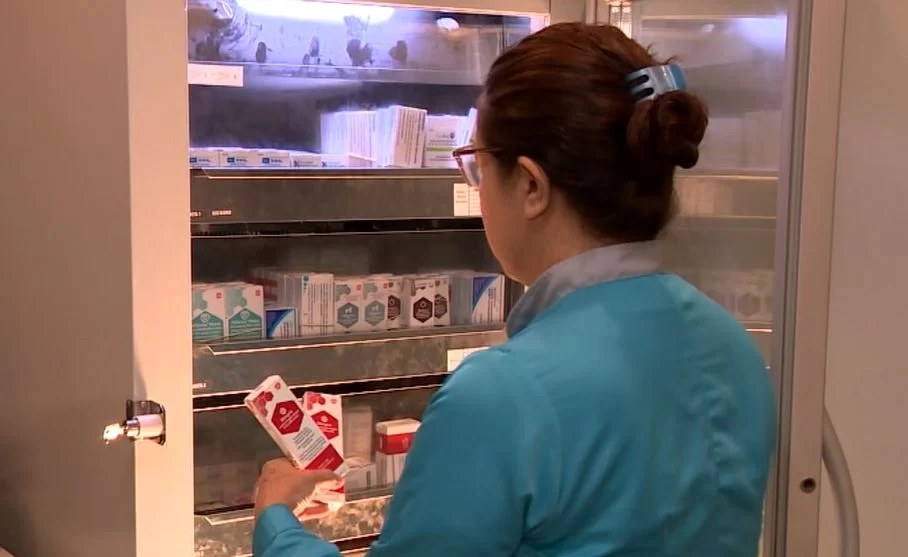 a foto mostra uma farmacêutica segurando várias caixas com medicamentos