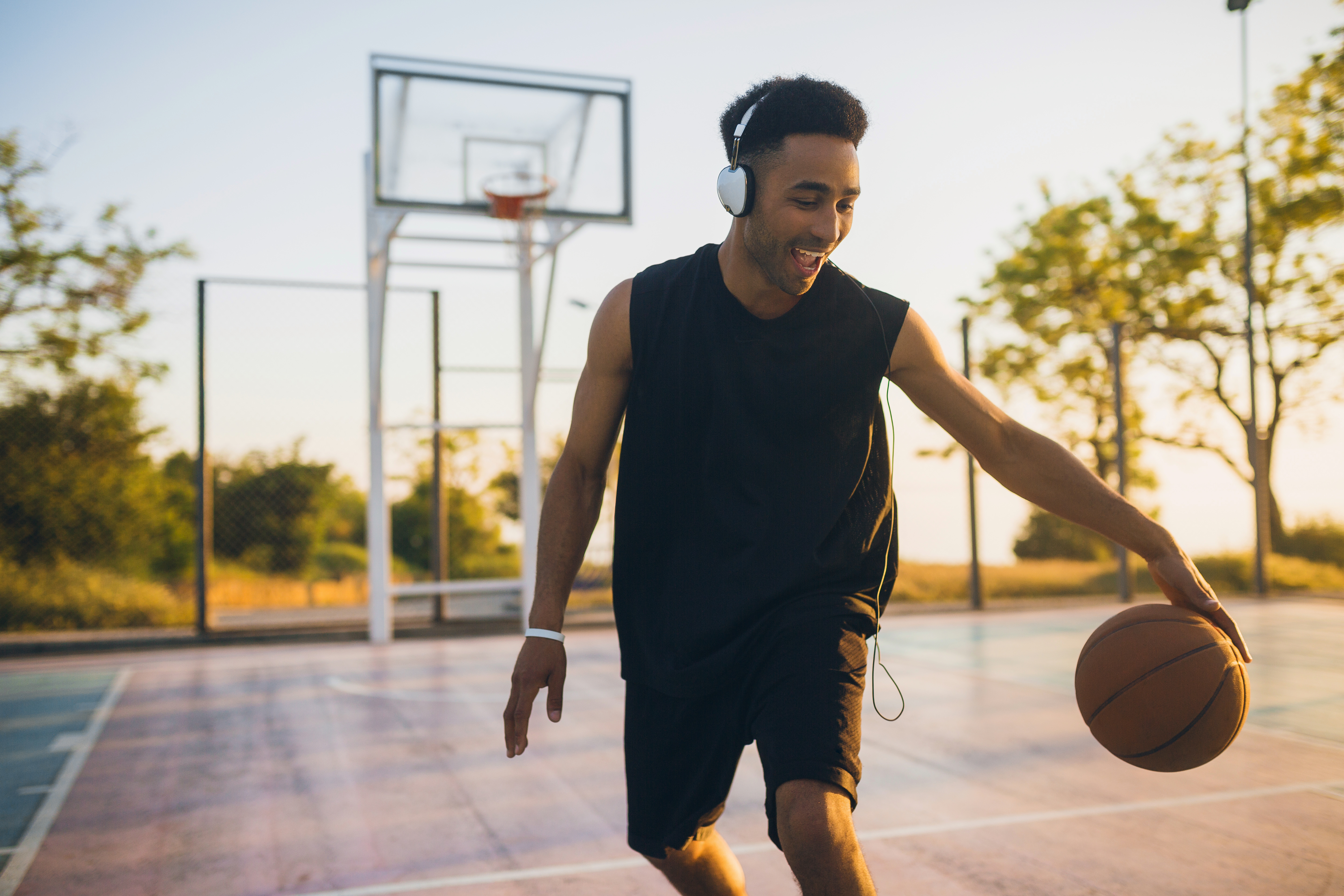 Jovem praticando esportes, jogando basquete ao nascer do sol