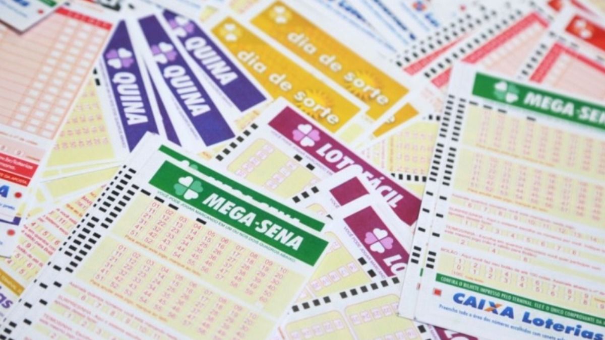Volantes de diversos tipos de jogos de loteria da Caixa Econômica Federal dispostos sobre uma mesa.