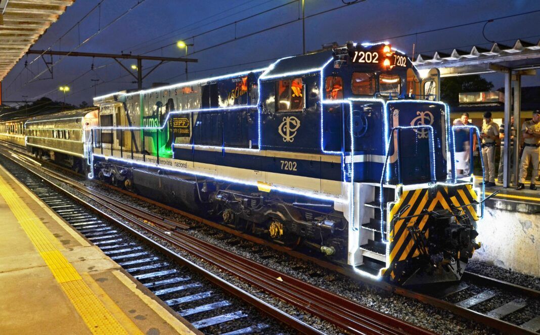 A foto mostra um trem iluminado com pisca-pisca natalinos