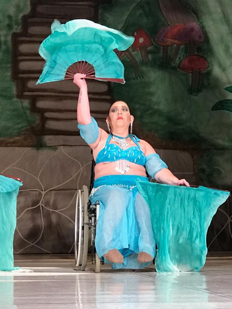 A foto mostra uma dançarina cadeirante com roupas de dança do ventre