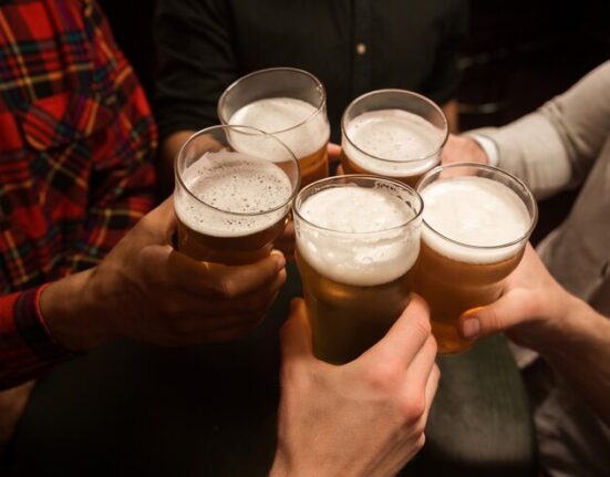 cinco mãos seguram copos cheios de cerveja
