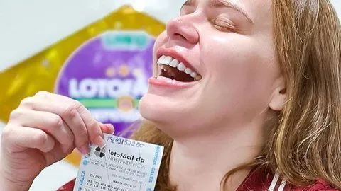 Na foto mostra a ex-BBB Paulinha Leite sorrindo e segurando o bilhete da loteria
