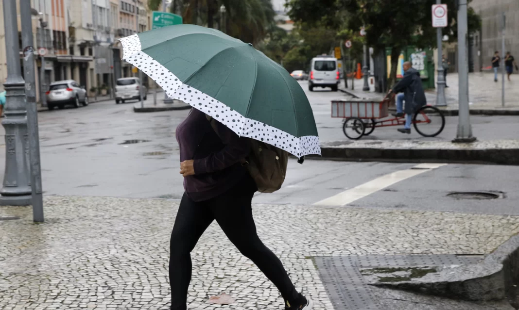 foto mostra mulher andando com um guarda-chuva na rua